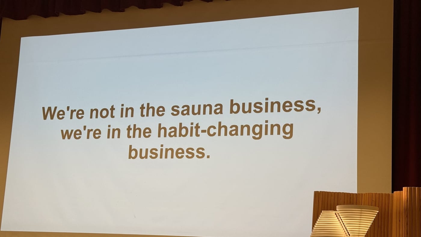 Diapositiva proyectada: We're not in the sauna business, we're in the habit-changing business, World Sauna Forum 2025